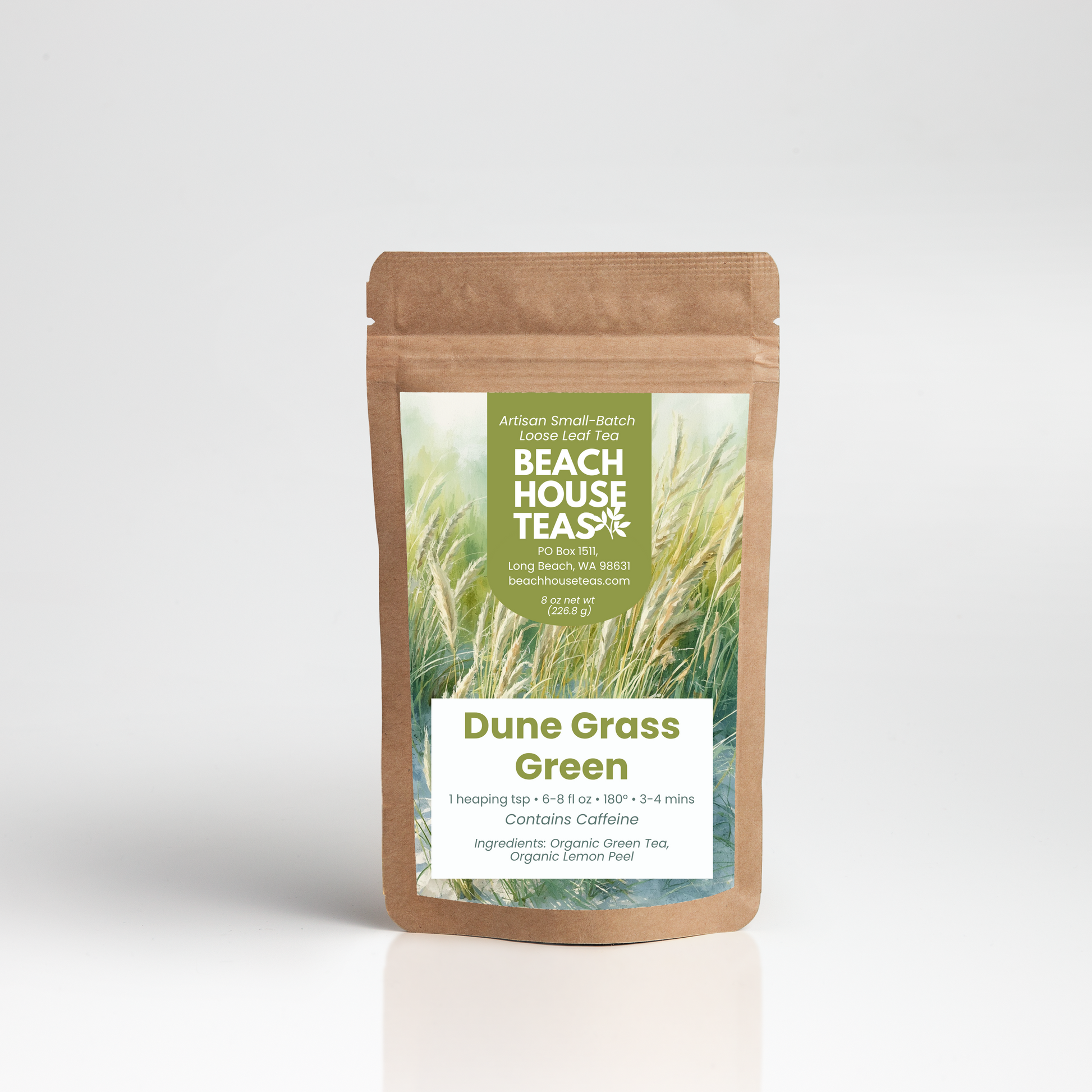 A stand-up kraft paper pouch of Beach House Teas Dune Grass Green tea, featuring a green and white label with an illustration of tall grass, set against a clean white background with a soft reflection.
