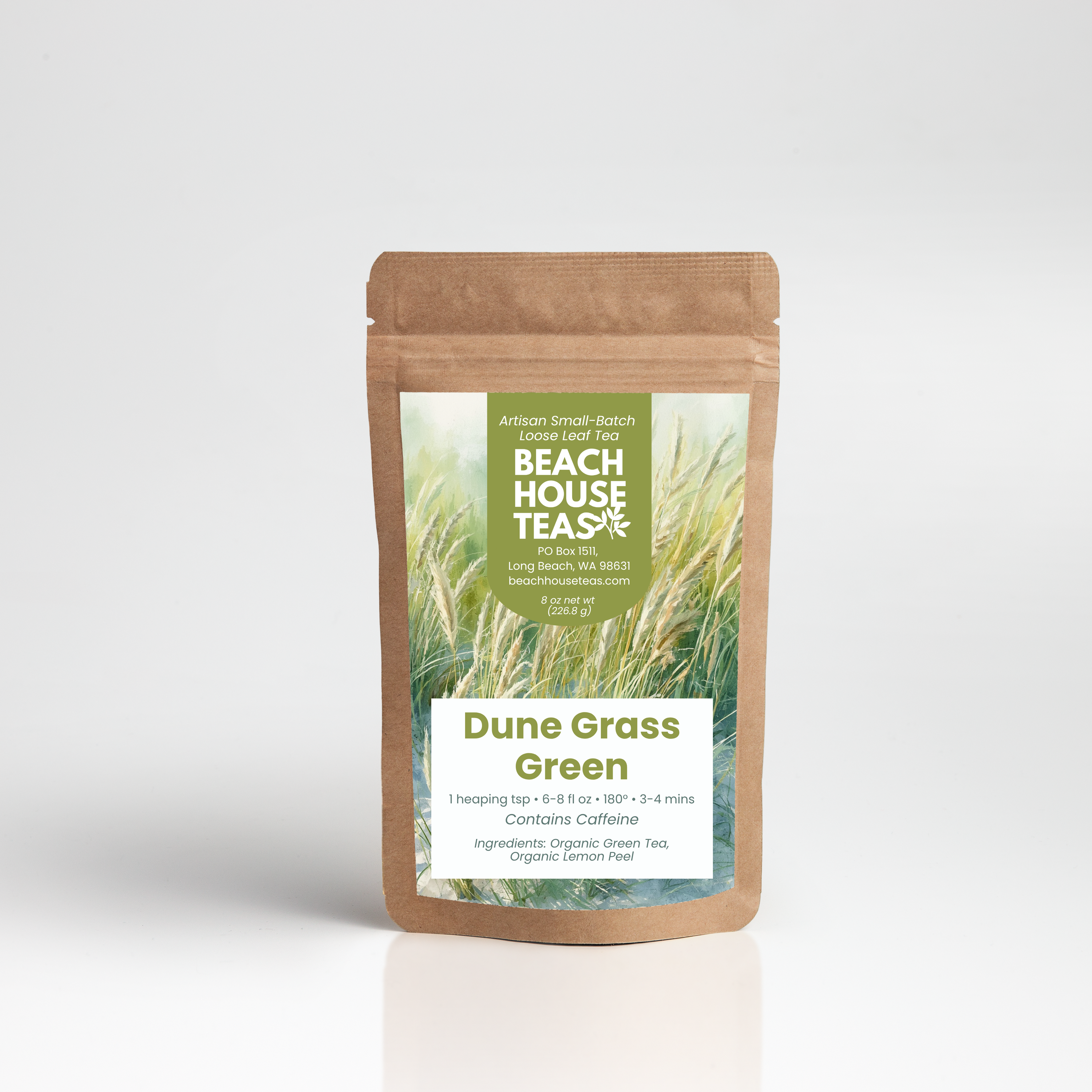 A stand-up kraft paper pouch of Beach House Teas Dune Grass Green tea, featuring a green and white label with an illustration of tall grass, set against a clean white background with a soft reflection.