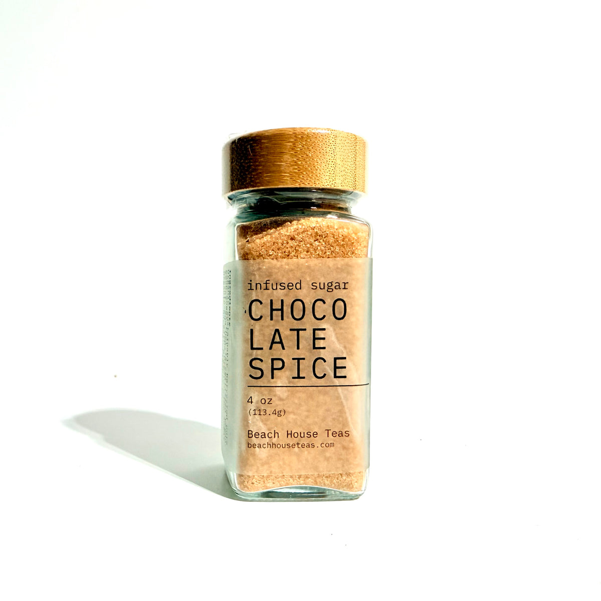 A small glass jar of Beach House Teas Choco Late Spice infused sugar, featuring a light brown wooden lid and a white label with black text, set against a plain white background with a soft shadow.