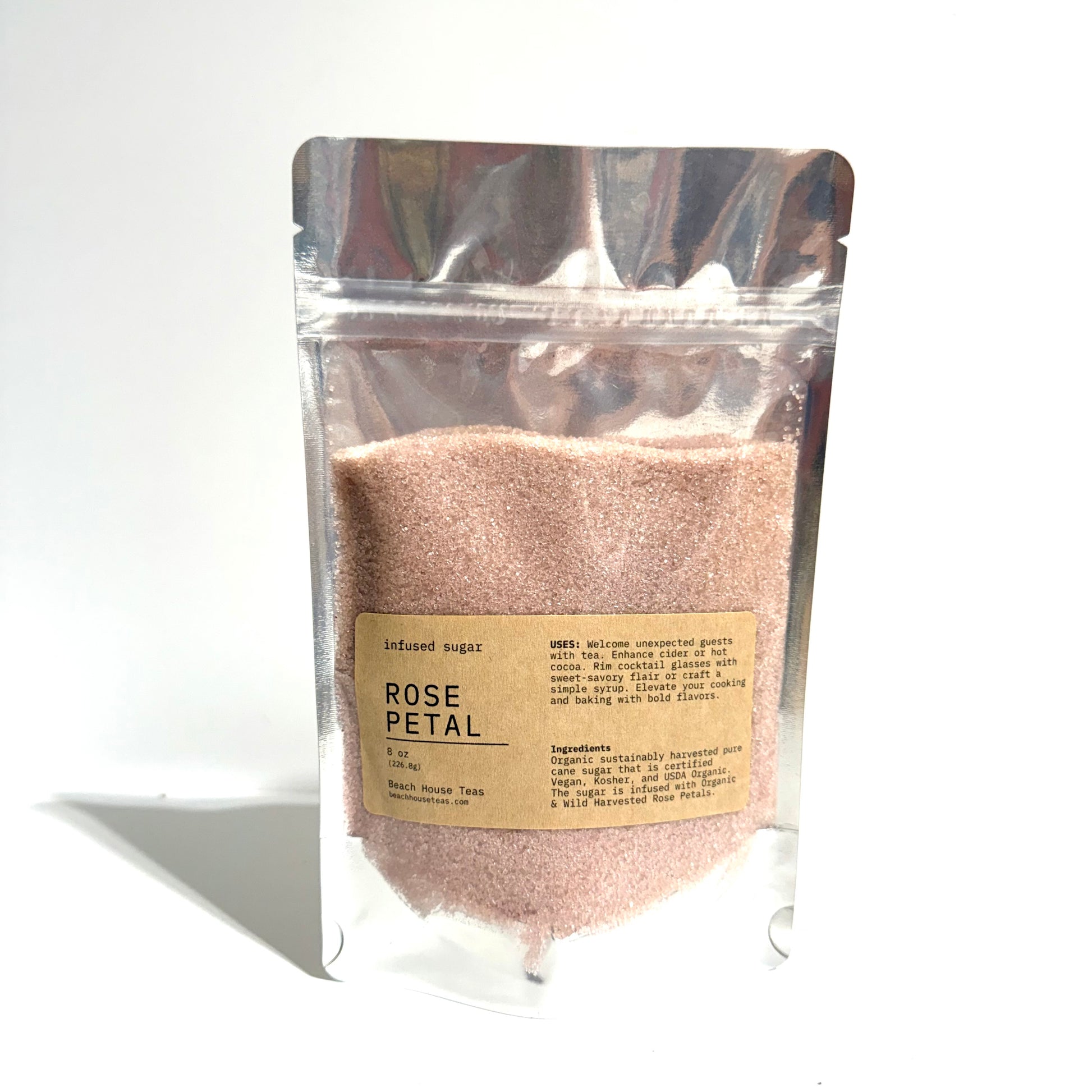 A stand-up resealable pouch of infused sugar labeled 'ROSE PETAL' on a white background. The pouch is transparent and filled with a light pinkish-brown granular powder, with a beige paper label on the front.