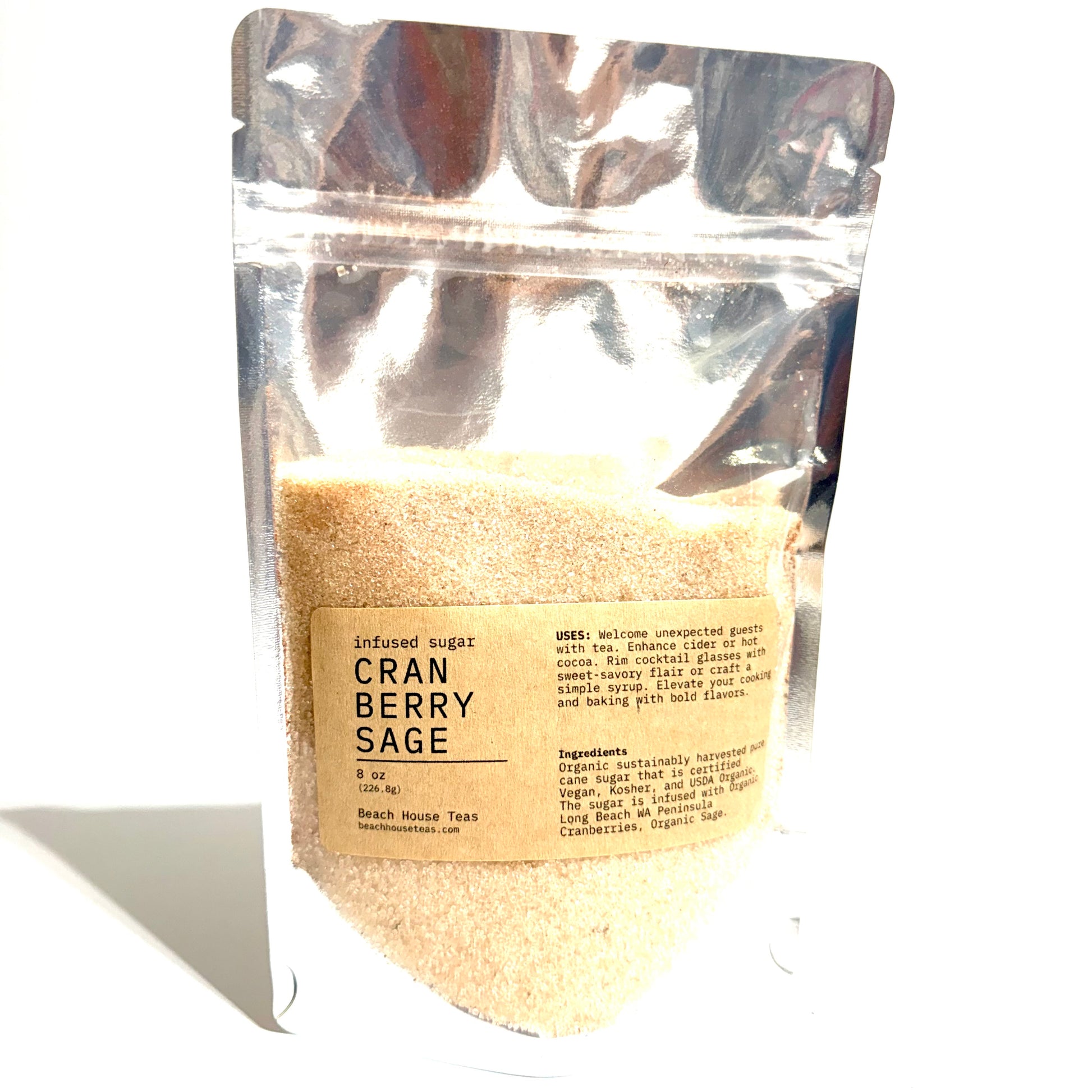A stand-up silver resealable pouch of Cran Berry Sage flavored sugar, showing a light tan granular contents through a clear window and a beige label, photographed on a white background.