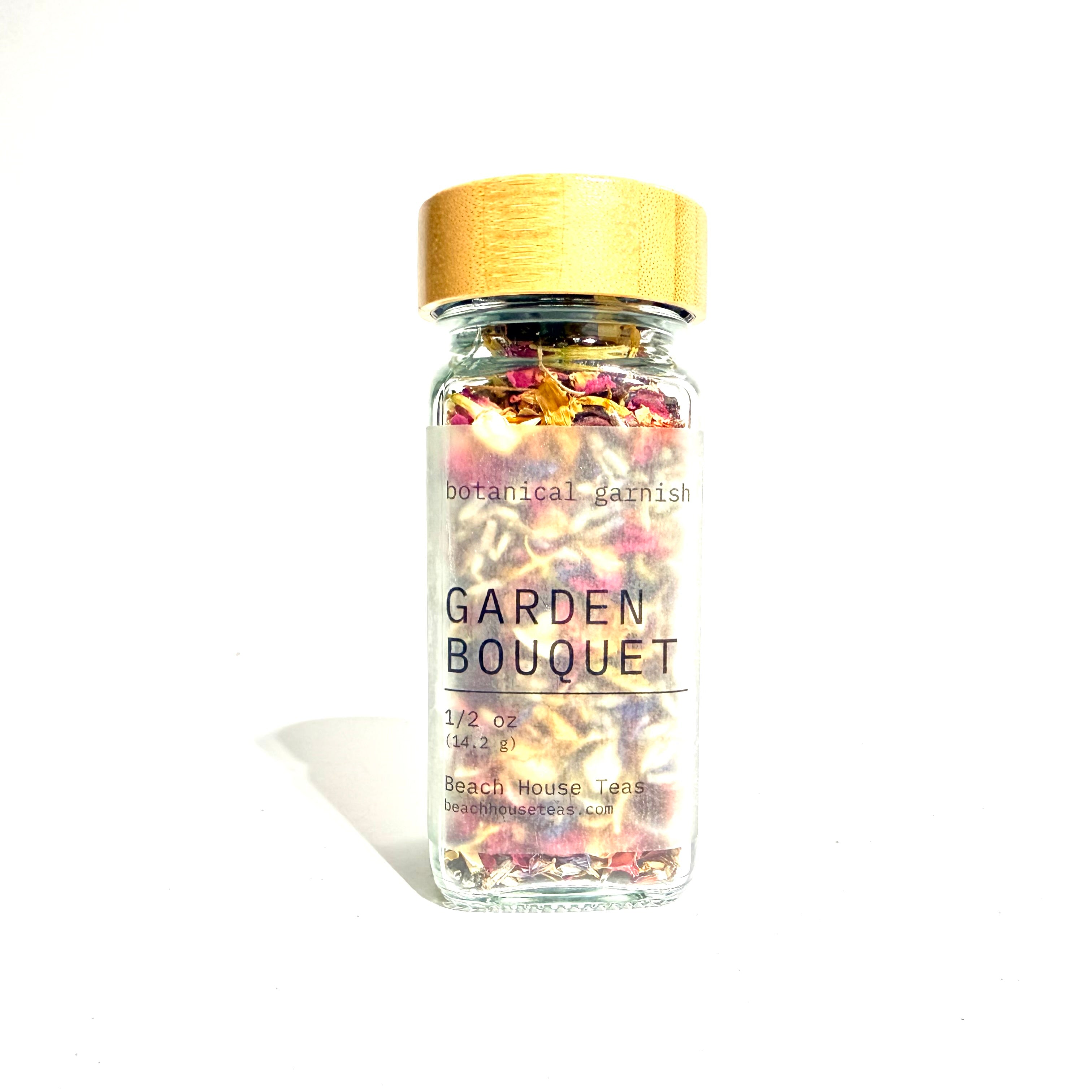 A clear glass jar filled with dried botanical flowers and herbs, topped with a light wood lid, labeled 'GARDEN BOUQUET' on a white background.
