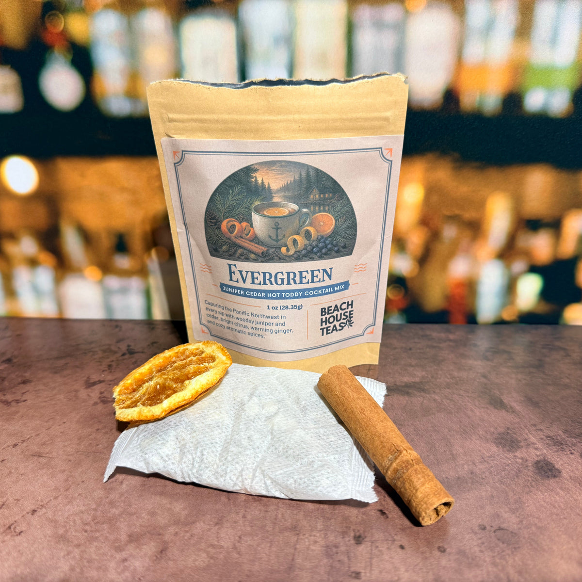 Evergreen hot toddy mix pouch with a sachet, dried orange slice, and cinnamon stick.