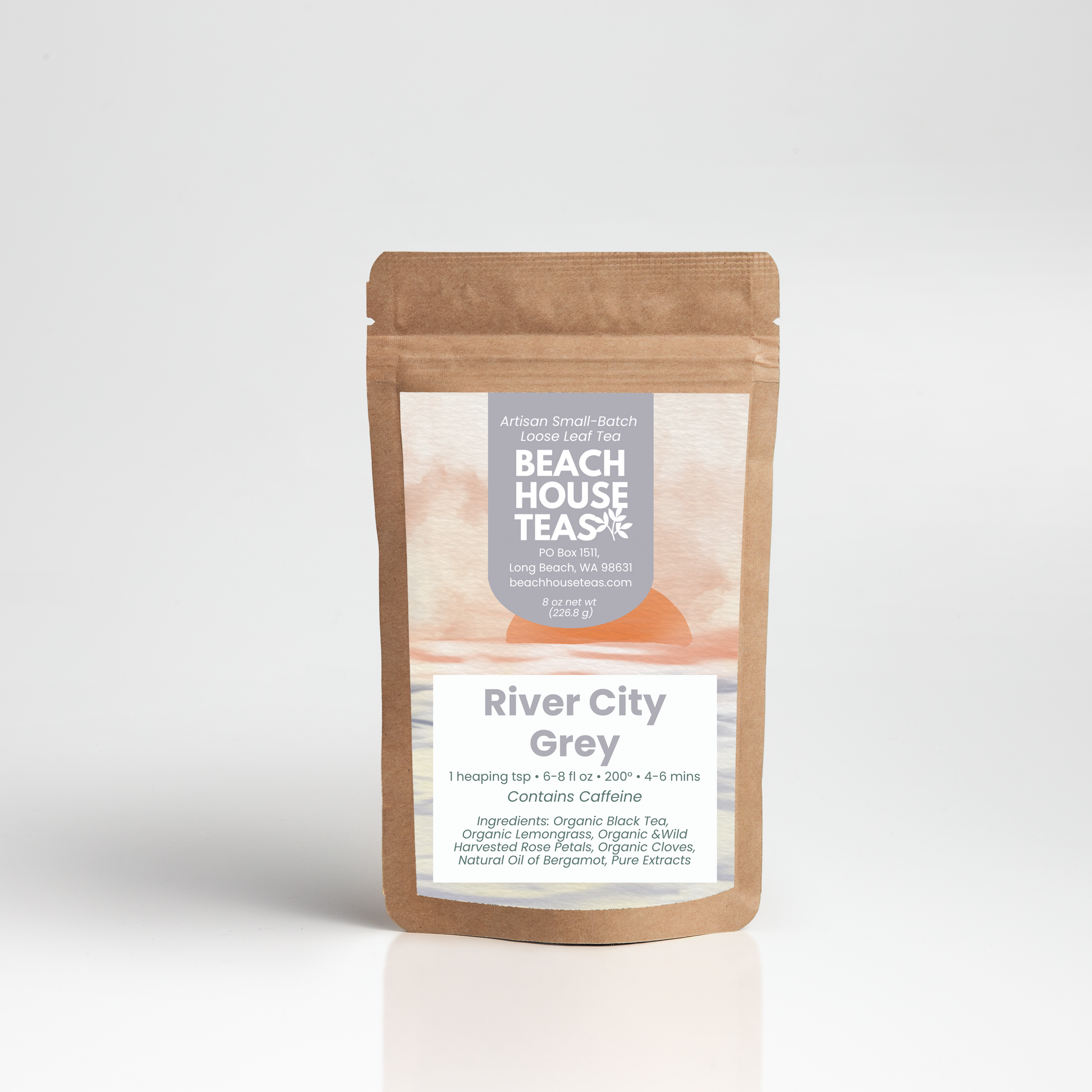 A stand-up kraft paper pouch of Beach House Teas River City Grey herbal tea, featuring a white and grey label with a peach-colored illustration, set against a clean white background with a soft reflection.