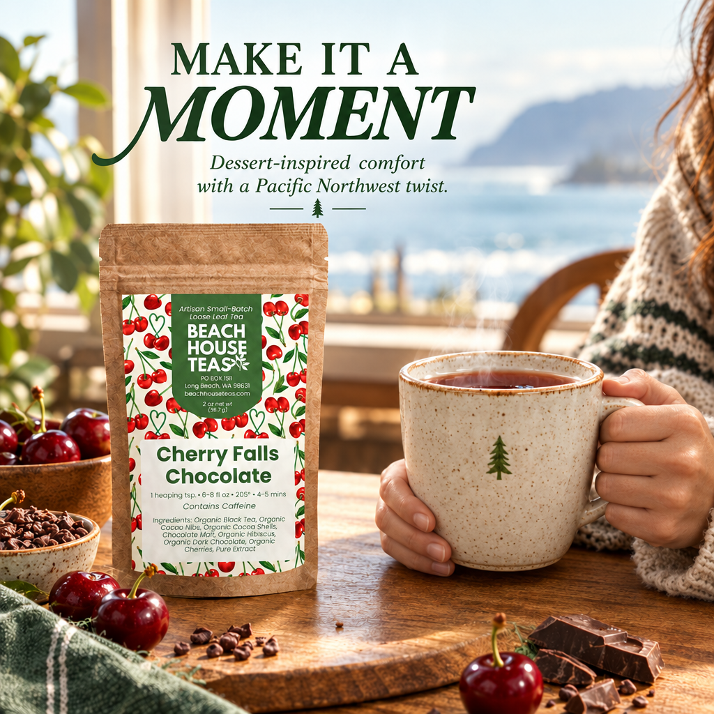 Hands holding a ceramic tea mug by its handle and base beside a Cherry Falls Chocolate pouch, cherries and dark chocolate.