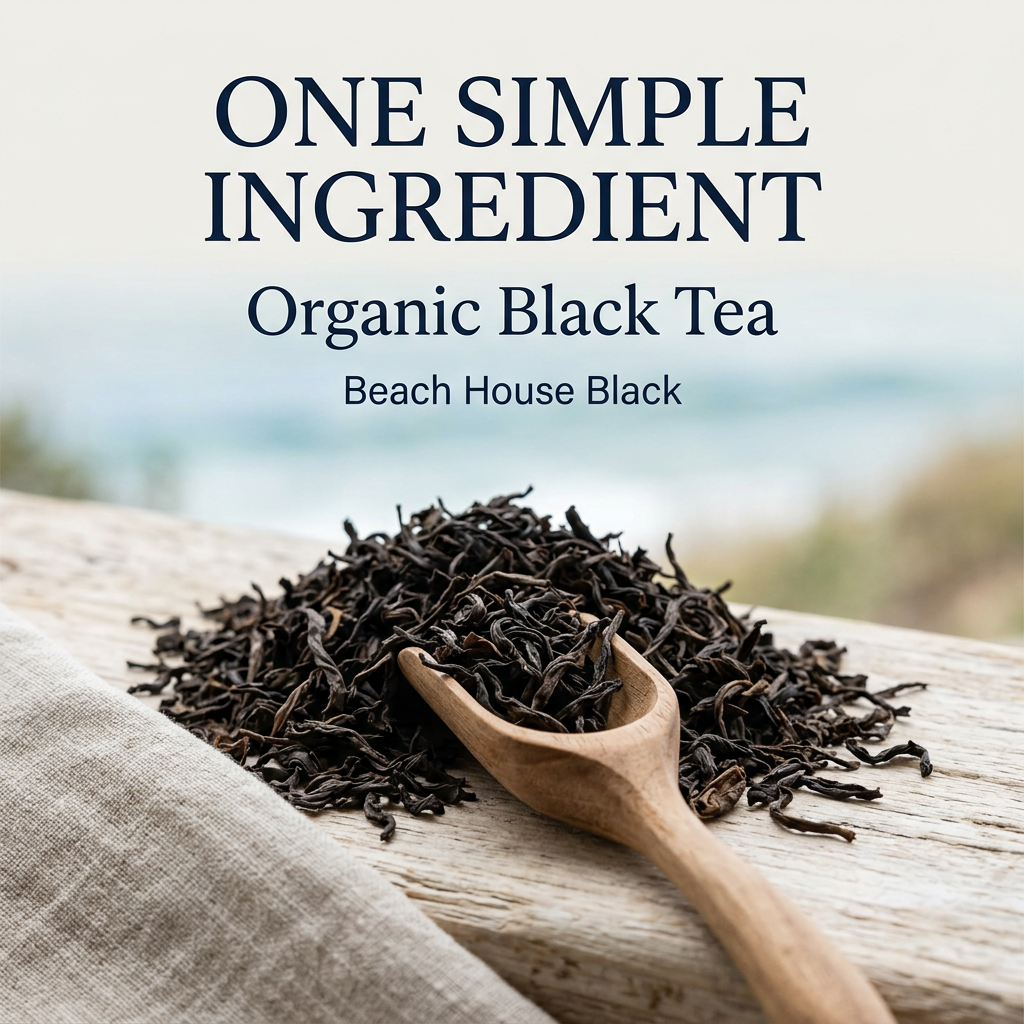 Beach House Black ingredients slide: One simple ingredient, Organic Black Tea. Dark loose black tea leaves and a wooden scoop on pale weathered wood, with a softly blurred coastal background.