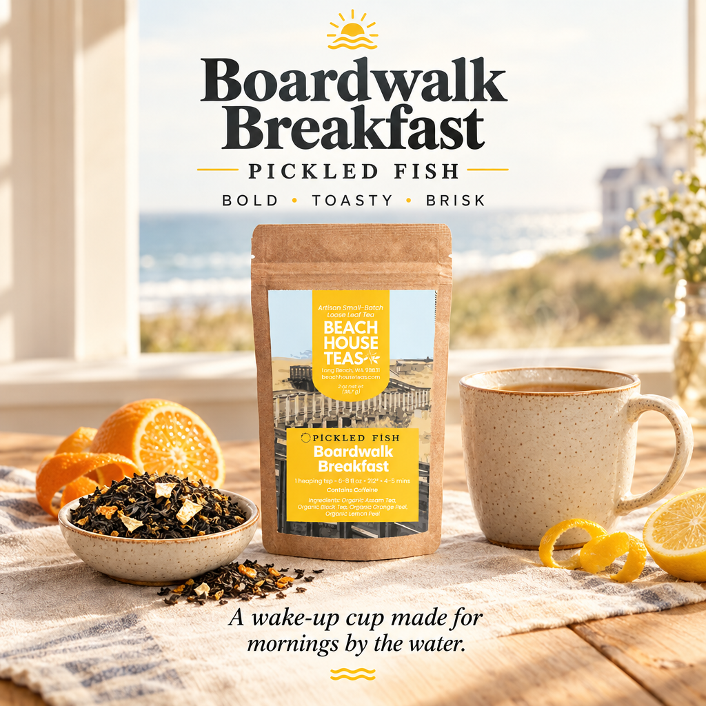 Boardwalk Breakfast tea pouch with loose black tea, orange, lemon and a ceramic mug on a coastal breakfast table.