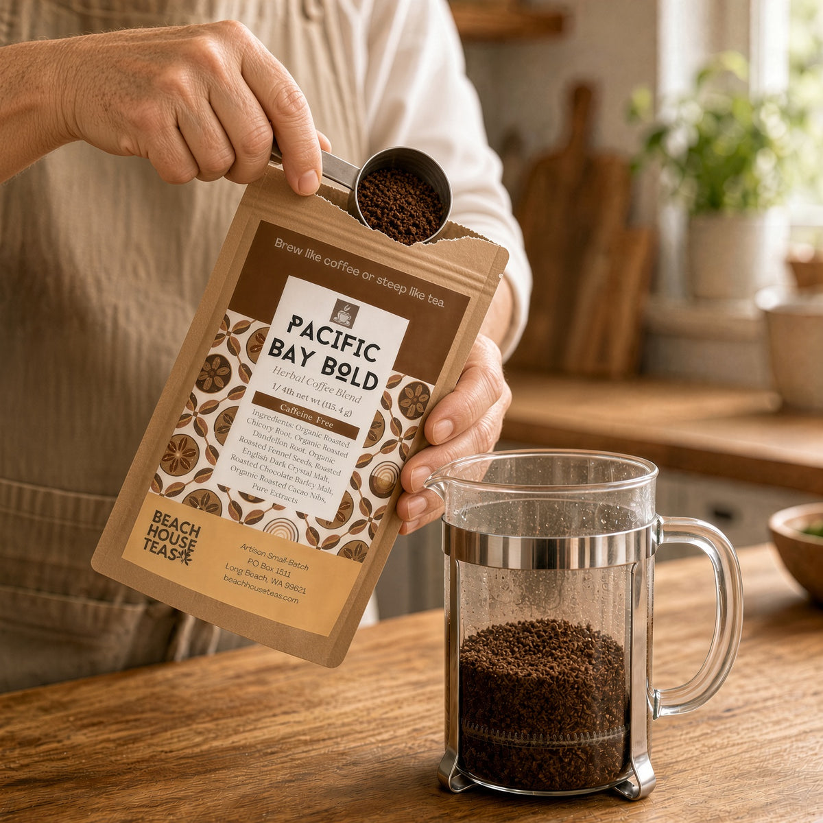 Person scooping Pacific Bay Bold herbal coffee from a kraft pouch beside a glass French press